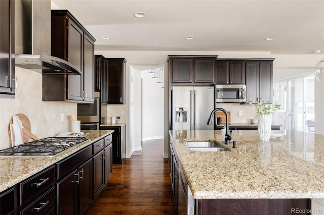 kitchen with dark brown cabinetry, stainless steel appliances, wall chimney exhaust hood, and a sink