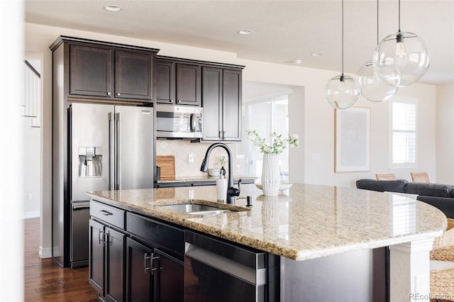 kitchen with an island with sink, a sink, dark wood-type flooring, dark brown cabinetry, and appliances with stainless steel finishes