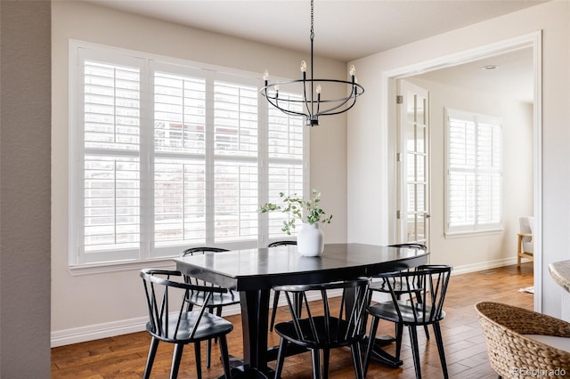 dining space featuring baseboards, an inviting chandelier, and wood finished floors