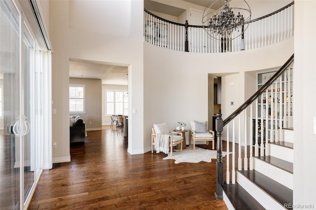 foyer entrance featuring stairs, a notable chandelier, baseboards, and wood-type flooring