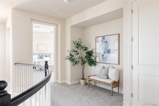 hall with visible vents, an upstairs landing, carpet, and baseboards