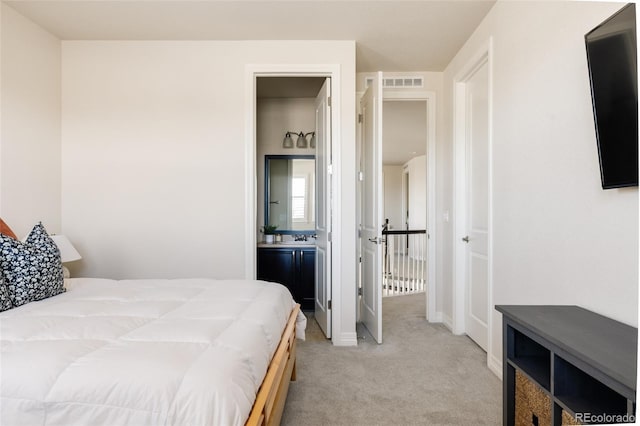 bedroom with visible vents, light carpet, and connected bathroom