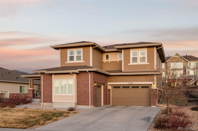 prairie-style home featuring a garage, brick siding, and driveway