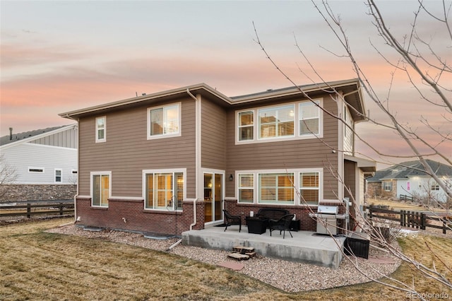 back of property with a patio, a yard, fence, and brick siding