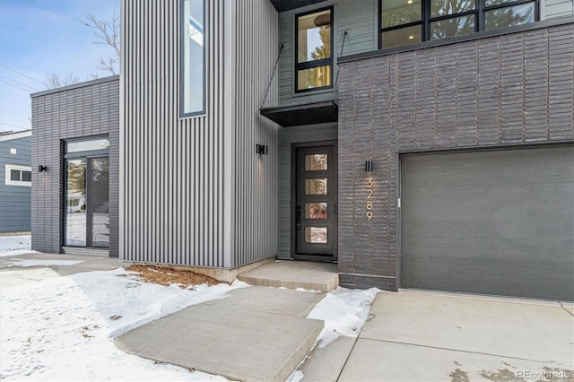 snow covered property entrance with a garage