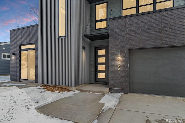 snow covered property entrance with a garage