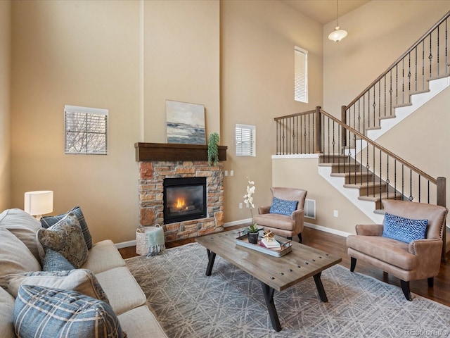 living area featuring stairway, a high ceiling, baseboards, and wood finished floors