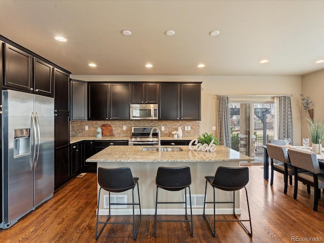 kitchen featuring stainless steel appliances, light stone countertops, tasteful backsplash, and dark wood-type flooring