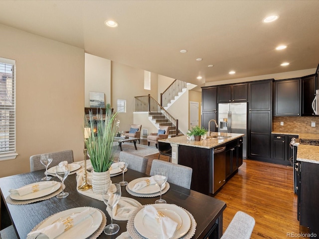 dining area featuring recessed lighting, wood finished floors, and stairs