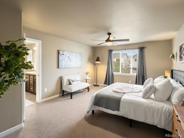 bedroom featuring baseboards, ceiling fan, ensuite bathroom, a textured ceiling, and light colored carpet