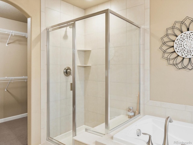 full bath featuring a garden tub, a stall shower, and a spacious closet