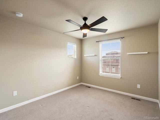 empty room featuring carpet flooring, baseboards, visible vents, and ceiling fan