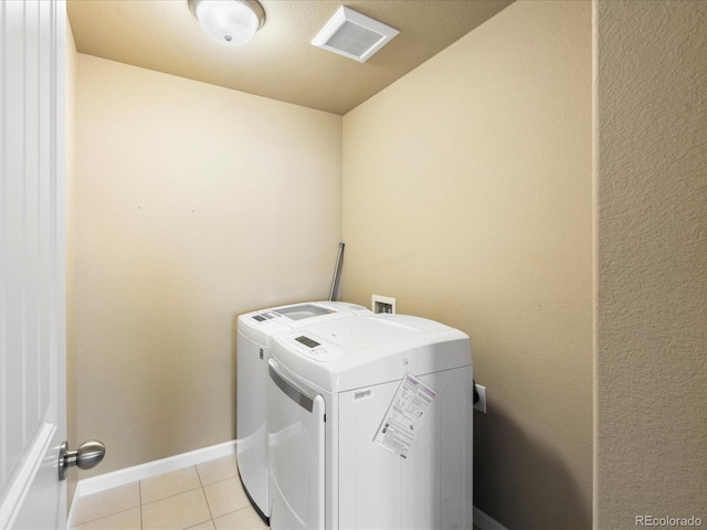 washroom with visible vents, light tile patterned flooring, baseboards, laundry area, and washing machine and clothes dryer