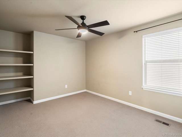 carpeted empty room with visible vents, baseboards, and a ceiling fan