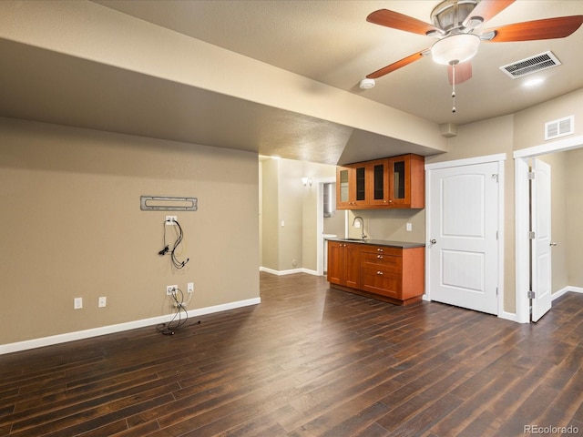 unfurnished living room with a sink, visible vents, and dark wood-style floors