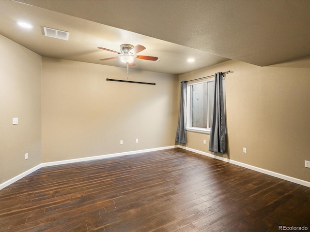 empty room featuring visible vents, baseboards, ceiling fan, and dark wood-style flooring