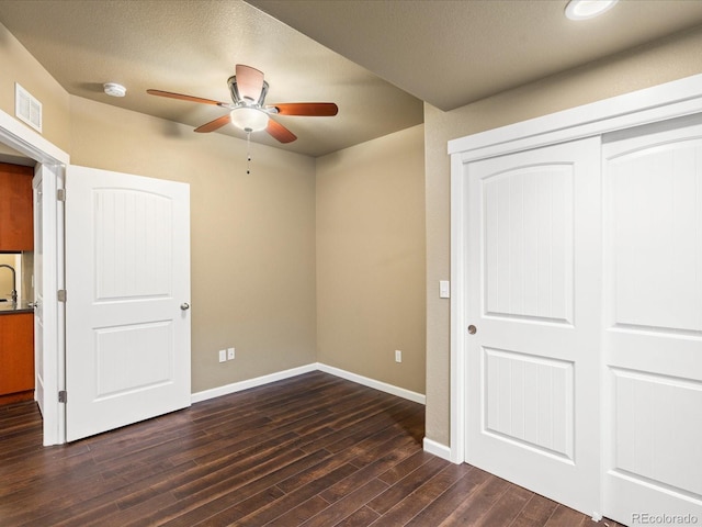 unfurnished bedroom with dark wood-style floors, visible vents, a closet, and baseboards