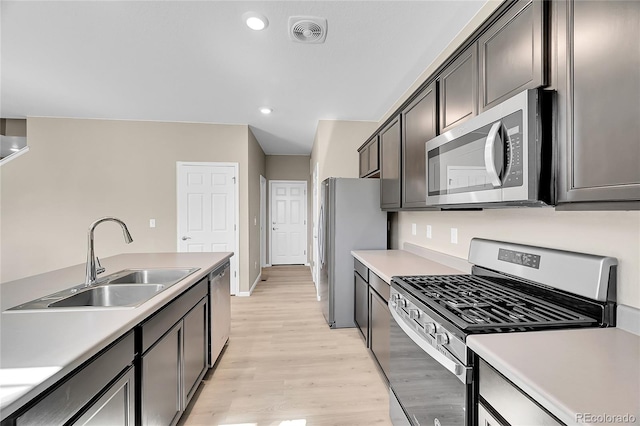 kitchen featuring visible vents, light wood-style flooring, a sink, stainless steel appliances, and light countertops