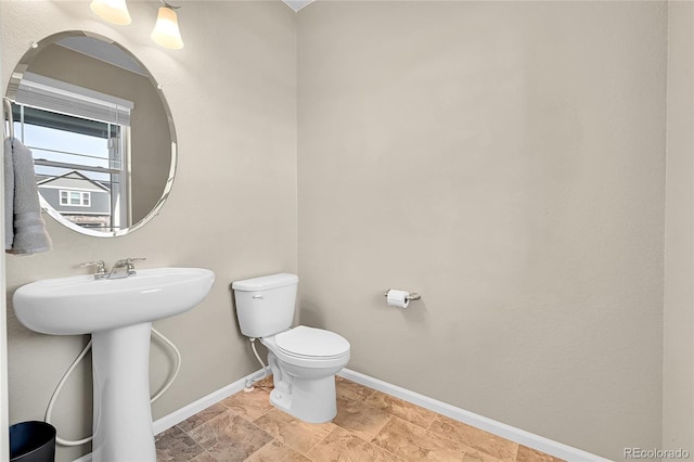 bathroom featuring a sink, baseboards, and toilet