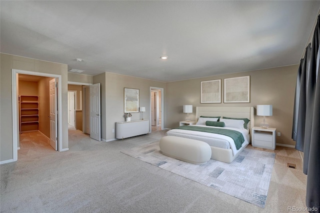 bedroom featuring a walk in closet, baseboards, and carpet