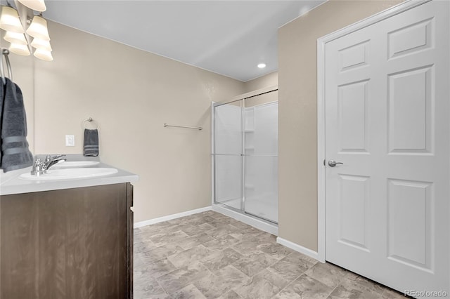 full bath with vanity, baseboards, a stall shower, and a chandelier