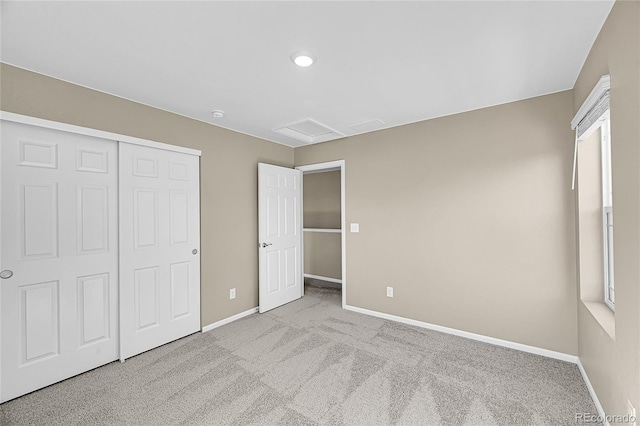 unfurnished bedroom with attic access, a closet, baseboards, and carpet floors