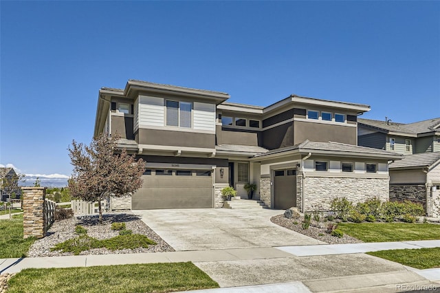 prairie-style home featuring an attached garage, stucco siding, driveway, and stone siding