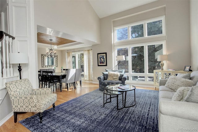 living room featuring an inviting chandelier, a healthy amount of sunlight, a tray ceiling, and hardwood / wood-style floors