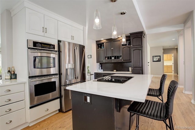 kitchen with light hardwood / wood-style floors, stainless steel appliances, a center island, and white cabinets