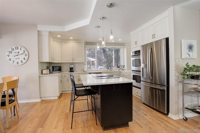 kitchen featuring white cabinetry, appliances with stainless steel finishes, a center island, and decorative backsplash