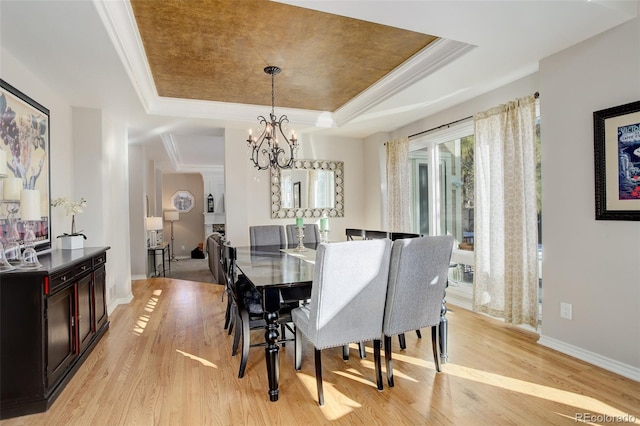 dining room featuring ornamental molding, a tray ceiling, light hardwood / wood-style flooring, and a notable chandelier