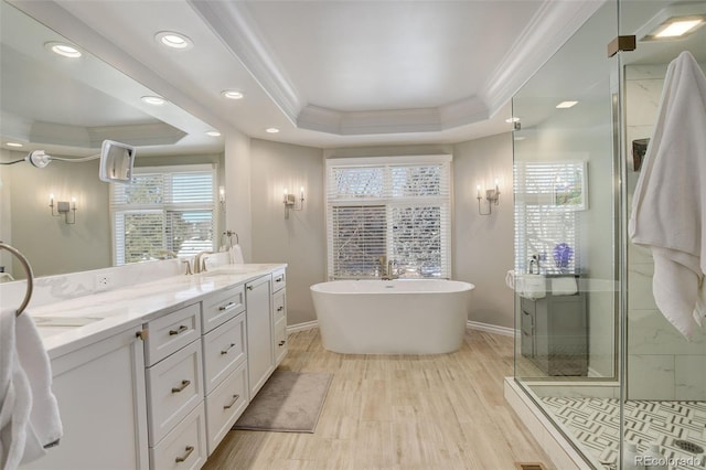 bathroom featuring vanity, a tray ceiling, wood-type flooring, ornamental molding, and separate shower and tub