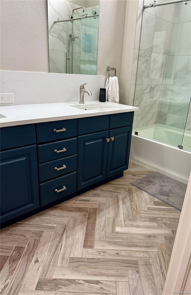 bathroom featuring parquet flooring, vanity, and bath / shower combo with glass door