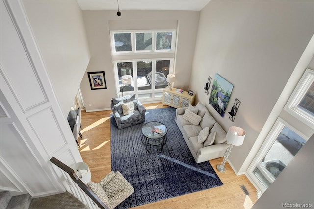 living room featuring light wood-type flooring and a high ceiling