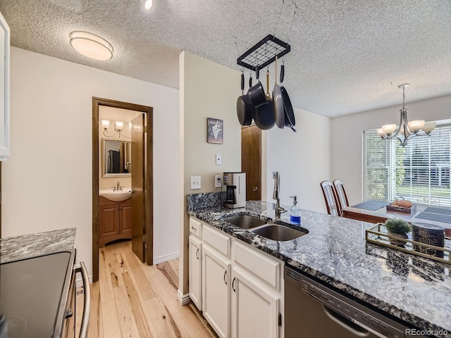 kitchen with black dishwasher, a chandelier, white cabinets, and a sink