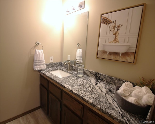 bathroom featuring baseboards, wood finished floors, and vanity