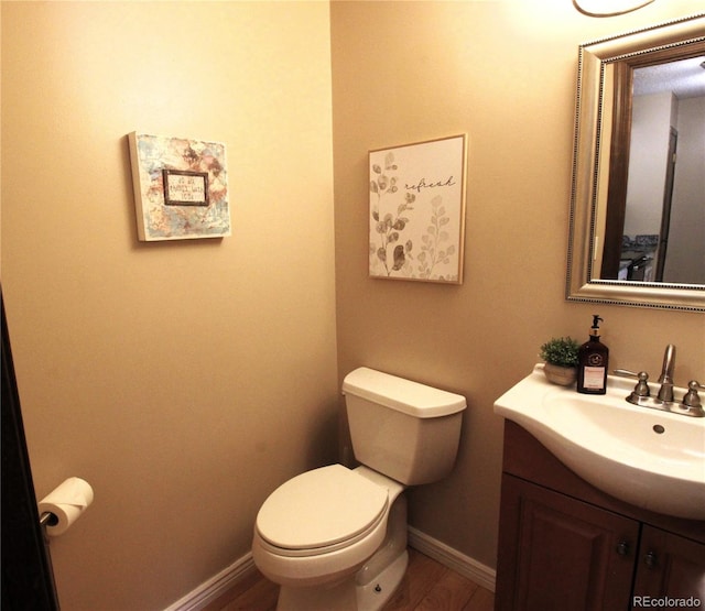 bathroom featuring toilet, wood finished floors, vanity, and baseboards