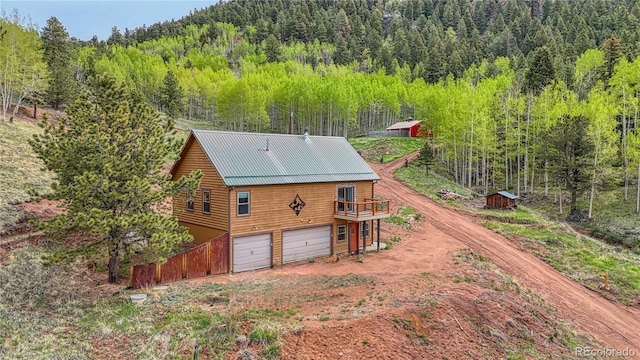 18766 State Highway 67, Divide, CO 80814 - back of property featuring driveway, a view of trees, an attached garage, a deck, and metal roof