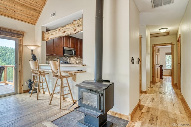 18766 State Highway 67, Divide, CO 80814 - kitchen featuring stainless steel microwave, light wood-style flooring, a kitchen bar, a wood stove, and vaulted ceiling