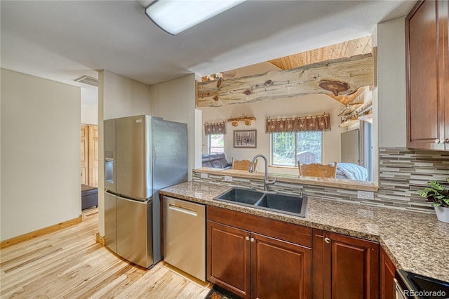 18766 State Highway 67, Divide, CO 80814 - kitchen with appliances with stainless steel finishes, a sink, light wood-style floors, decorative backsplash, and brown cabinetry