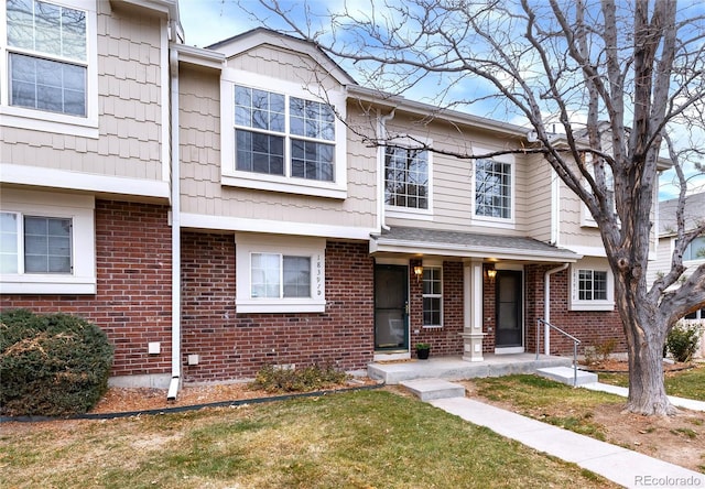 townhome / multi-family property featuring covered porch and brick siding