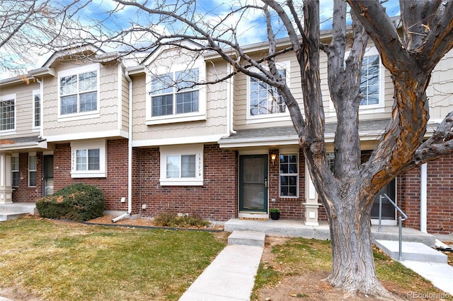 view of property with brick siding and a front lawn