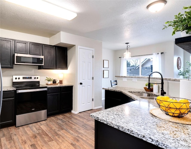 18397 E Alabama Pl Unit D, Aurora, CO 80017 - kitchen with appliances with stainless steel finishes, a sink, light wood finished floors, a textured ceiling, and light stone counters