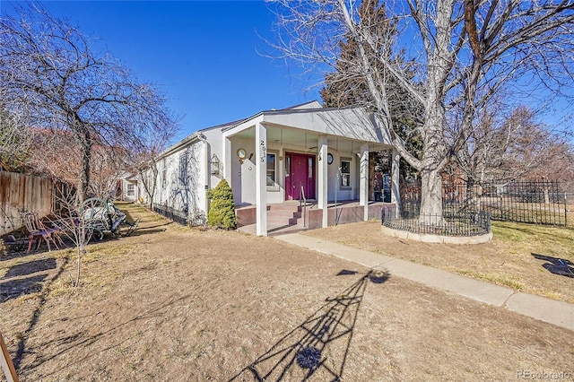 view of front of home with stucco siding, a porch, and fence