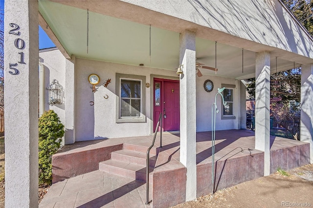 doorway to property featuring covered porch and stucco siding