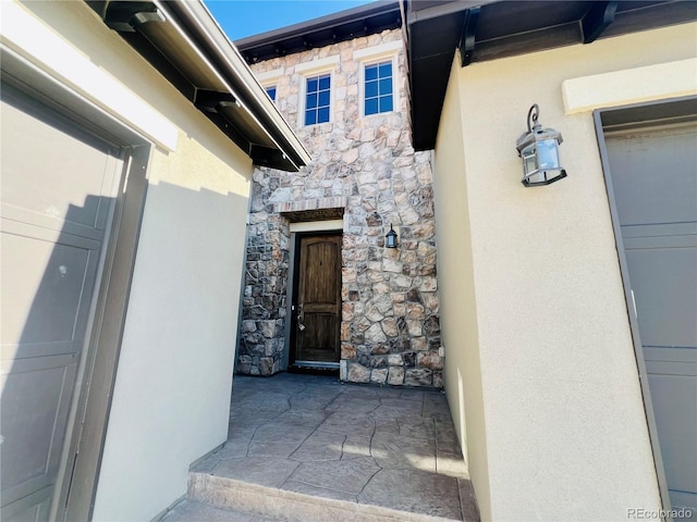 entrance to property with stone siding and stucco siding