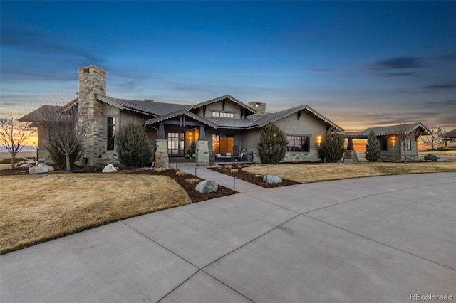 3947 Taliesin Way, Fort Collins, CO 80524 - view of front facade featuring driveway, stone siding, a front yard, and a chimney