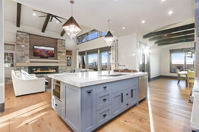 3947 Taliesin Way, Fort Collins, CO 80524 - kitchen with light wood finished floors, beam ceiling, a fireplace, gray cabinets, and stainless steel dishwasher