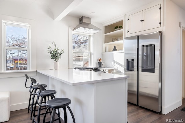 kitchen with appliances with stainless steel finishes, kitchen peninsula, a breakfast bar area, and white cabinets