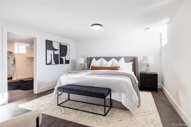 bedroom with a closet, dark hardwood / wood-style flooring, and a walk in closet